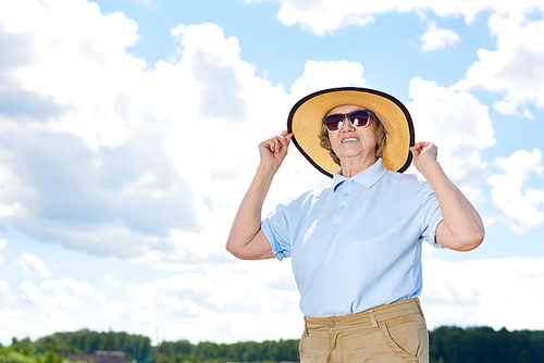 Portrait of active senior woman enjoying hiking trip wearing straw hat and  looking away, copy space