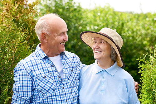 Portrait of loving senior couple embracing tenderly posing for camera in beautiful garden and looking at each other