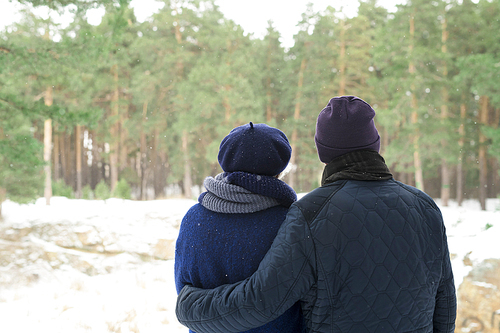 Back view portrait of senior couple looking at view of winter forest while enjoying walk, copy space