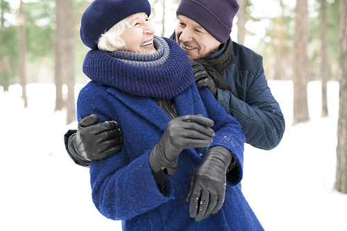 Waist up portrait of playful senior couple enjoying walk in winter forest