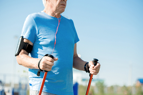 Mid section portrait of active senior man practicing Nordic walking with poles outdoors in park, copy space