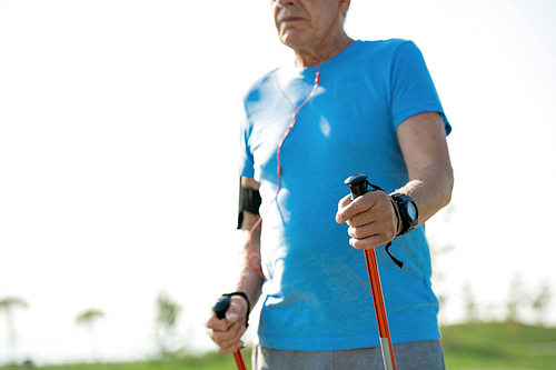 Mid section portrait of active senior man practicing Nordic walking with poles outdoors in park, copy space