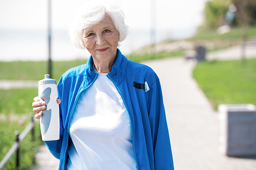 Waist up portrait of active senior woman  and holding water bottle while enjoying morning run in park, copy space