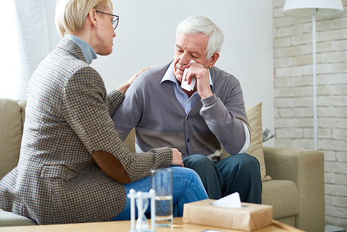 Portrait of female psychiatrist comforting senior man crying during therapy session, copy space