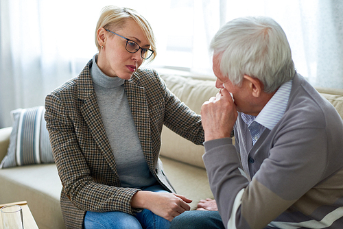 Portrait of female psychiatrist comforting senior man crying during therapy session