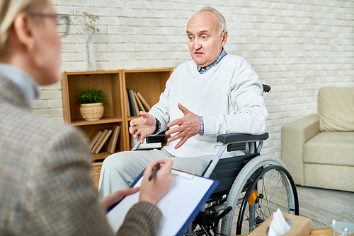 portrait of . senior man in wheelchair sharing problems with psychiatrist during therapy session, copy space