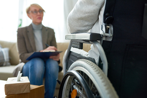 Portrait of  female psychiatrist interviewing handicapped  man during therapy session, copy space