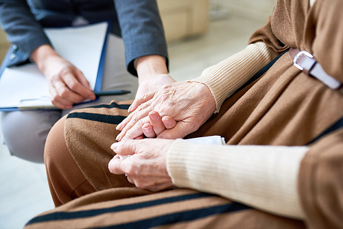 Close up of female psychologist holding hand of senior patient during therapy session, copy space