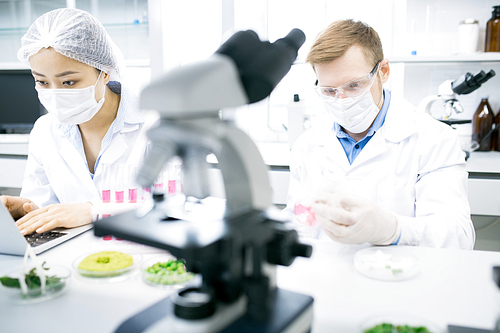 Front view portrait of two young scientists studying substances while working on research in modern  medical laboratory