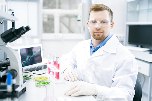 Portrait of smiling young scientist wearing lab coat  while  working on research in laboratory