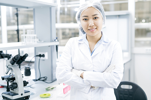 Waist up portrait of Asian female scientist  smiling happily while doing research in medical laboratory, copy space