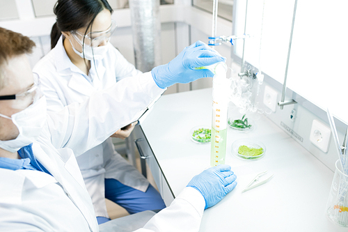 High angle portrait of two scientists working on food research studying liquids in beaker while sitting at table in laboratory