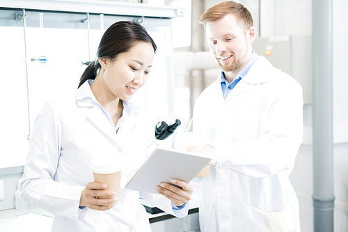 Waist up portrait of two modern young scientists wearing lab coats taking break from working in medical laboratory