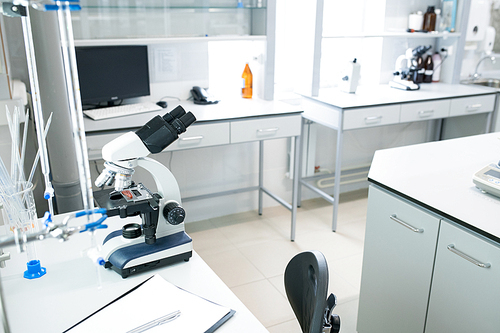 Microscope on table in empty science laboratory, copy space