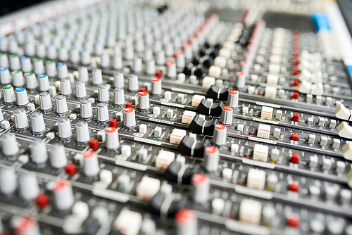 Close-up shot of colorful knobs on music mixer control panel in sound studio.