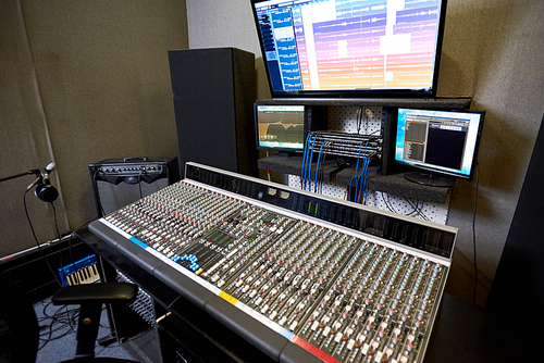 Interior shot of modern control console and monitors in contemporary music recording studio.