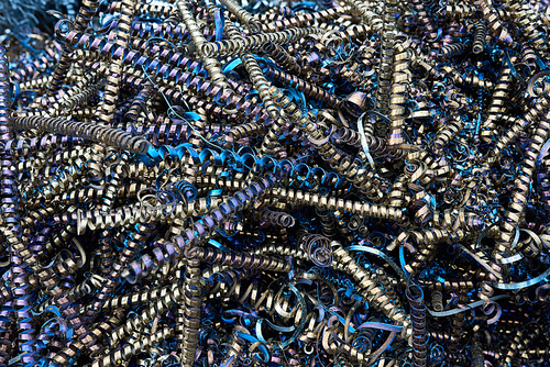 Close up of metal spiral shavings or springs at metalworking plant, copy space background