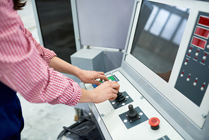 High angle close up of female hands pushing buttons on electronic control panel of modern machine unit at factory