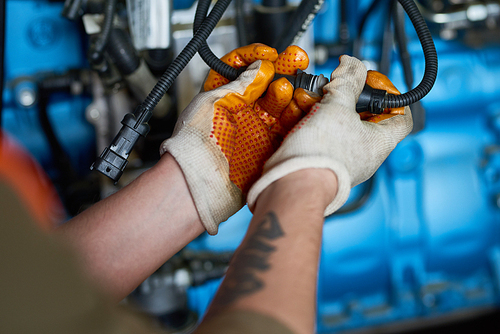 Close up of unrecognizable factory worker wearing gloves connecting cables repairing electricity in power unit, copy space