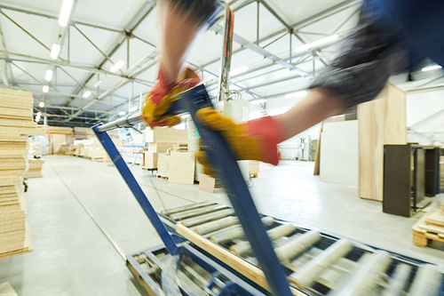 Close-up of unrecognizable workman adjusting metal handle while regulating roller conveyor at furniture factory