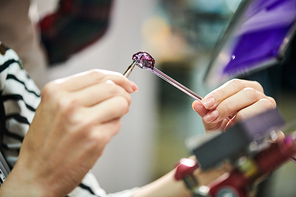 Close up of unrecognizable woman shaping glass while making beautiful handmade jewelry in glassworking studio, copy space