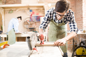 Portrait of focused modern carpenter working with wood in joinery shop, copy space