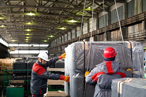 Waist up portrait of two factory workers packing and moving materials in workshop of modern plant, copy space