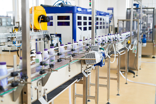 Industrial dairy production. Modern conveyor belt with raw of plastic milk bottles.