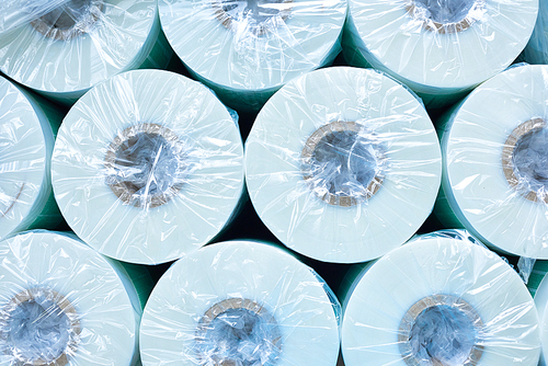 Top view of several round paper rolls packed in plastic at modern factory, production and recycling concept, copy space