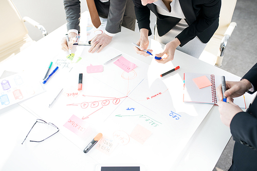 High angle view at unrecognizable businesspeople drawing charts standing at table in conference room and planning strategy, copy space