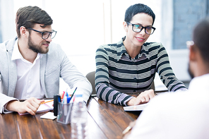 Two young employers having an interview with emloyee at the table at office