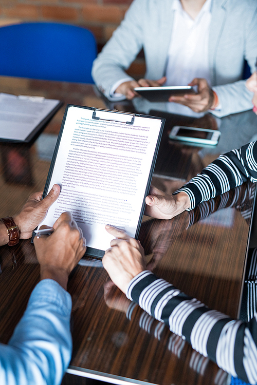 Close-up of unrecognizable man signing important contract, business lady pointing at text while asking to pay attention