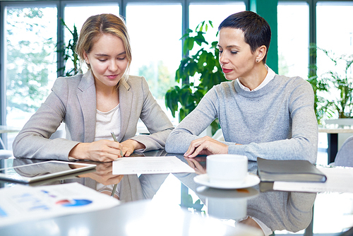 Group portrait of confident white collar workers gathered together at spacious boardroom and studying statistic data with interest