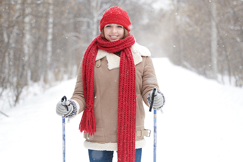 Waist up portrait of beautiful  young woman smiling happily  while enjoying skiing in snowy winter forest, copy space