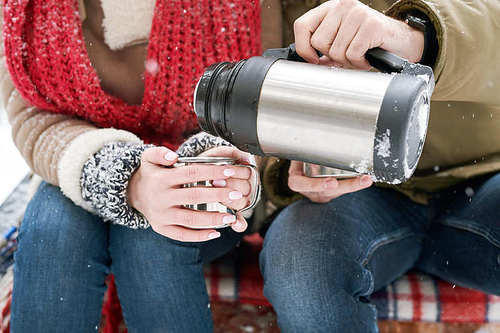 Close up of unrecognizable young couple enjoying hot cocoa during date in winter outdoors