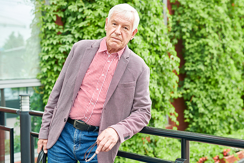 Waist up portrait of modern senior man dressed in business casual posing standing on terrace outdoors, copy space
