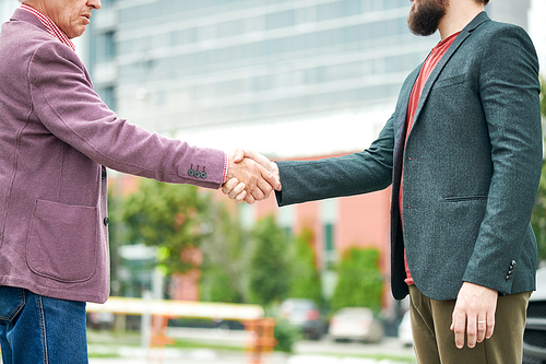 Mid section side view portrait of successful senior businessman shaking hands with partner outdoors, copy space