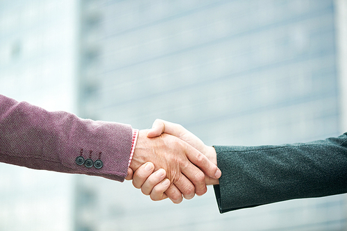 Side view close up of successful senior businessman shaking hands with partner outdoors in city, copy space