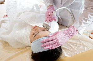 High angle portrait of pretty brunette woman enjoying beauty treatment in  cosmetologist office, copy space