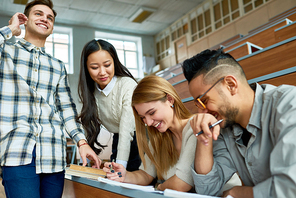 Multi-ethnic group of students having fun  and laughing  in lecture hall of modern college while enjoying classes, focus on beautiful young woman