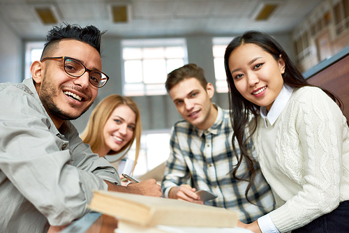 Multi-ethnic group of cheerful students  and smiling sitting at desk in lecture hall of modern college