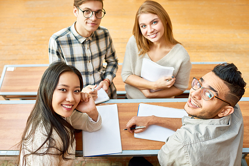 High angle view at multi-ethnic group of cheerful students  and smiling sitting at desk in lecture hall of modern college