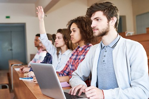 Group of students sitting at lesson in a row with laptop