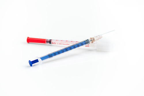 Closeup shot of two disposable insulin syringes crossed isolated on white, medicine and treatment concept