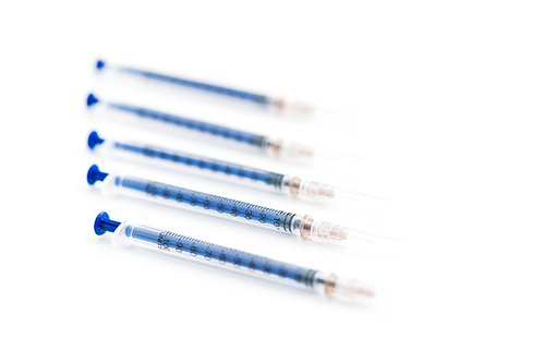 Closeup of five disposable insulin syringes in row isolated on white, medicine and treatment concept