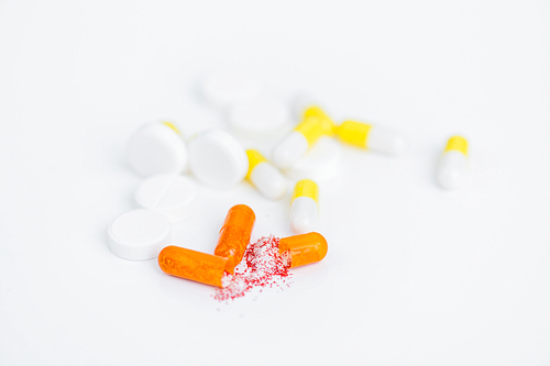 Closeup shot of opened gelatin capsule with drug substance spilling on white background, medication concept