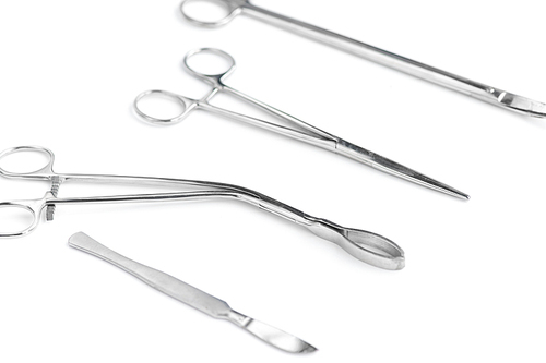 Closeup of surgical instruments in row on white background, surgical scissors, scalpel and tongs