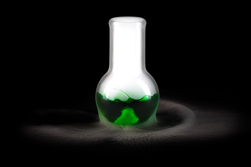 Close up of glass flask with green liquid  and steam pouring from it on black background, copy space