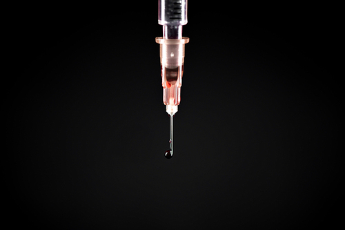 Extreme close up of insulin syringe needle on black background, copy space