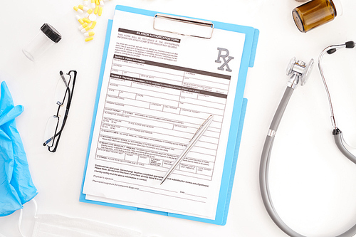 Top view flatlay of doctors tools on white desk composition of patients form on  clipboard, glasses and stethoscope, copy space
